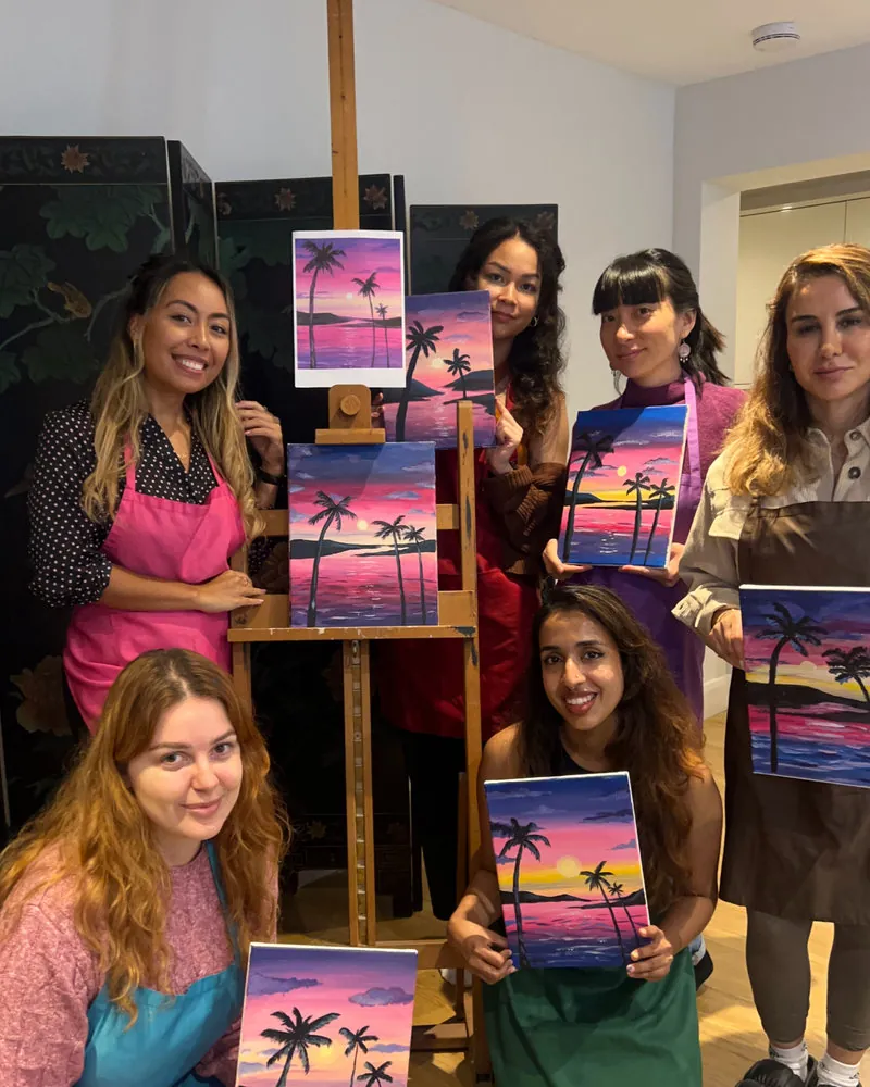 A Paint with MI group holding up their finished sunset paintings