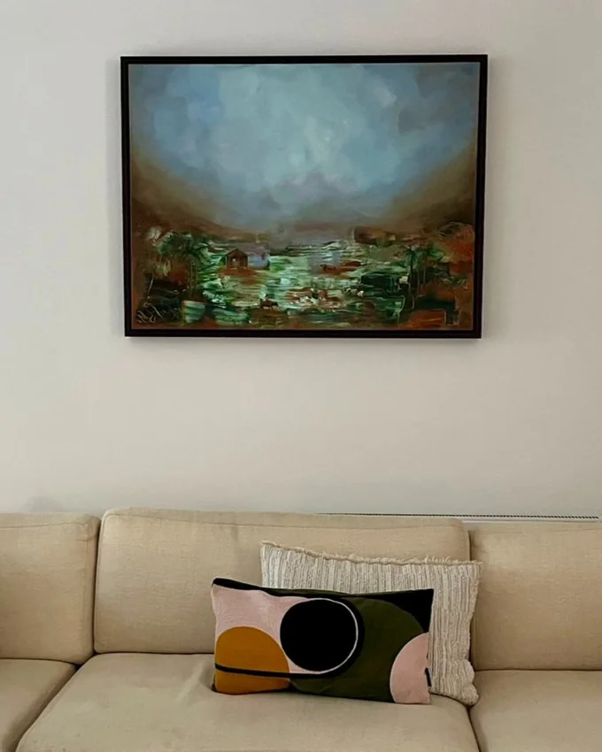 Terracotta Barrio, a misty green and blue landscape, hanging above a sofa